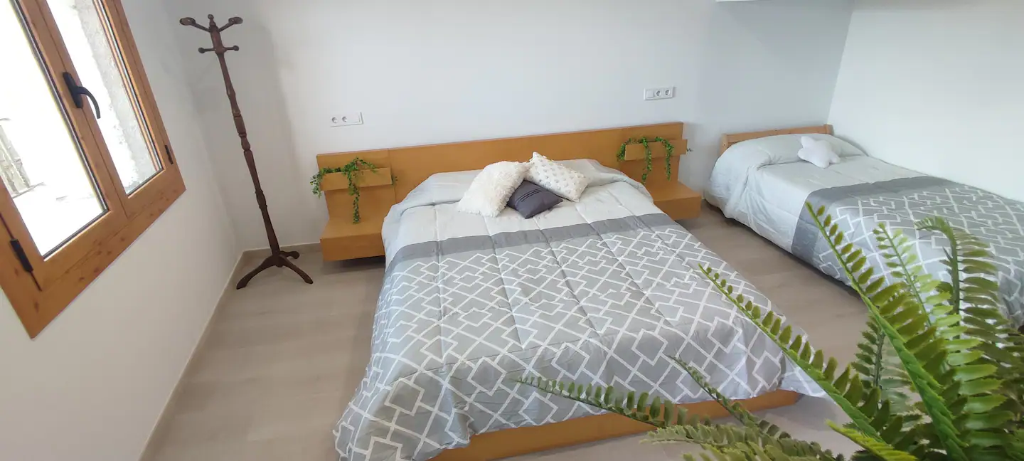 Dormitorio con cama de matrimonio y una individual grande, junto a la ventana