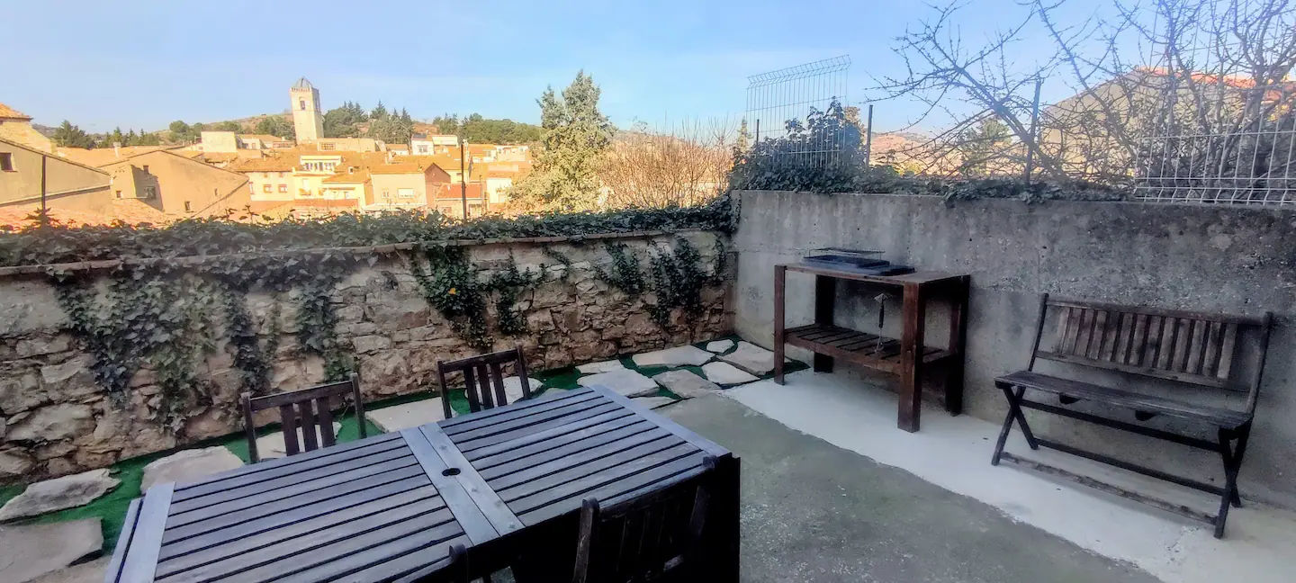 Patio con mesa de comedor exterior, bancos y la barbacoa