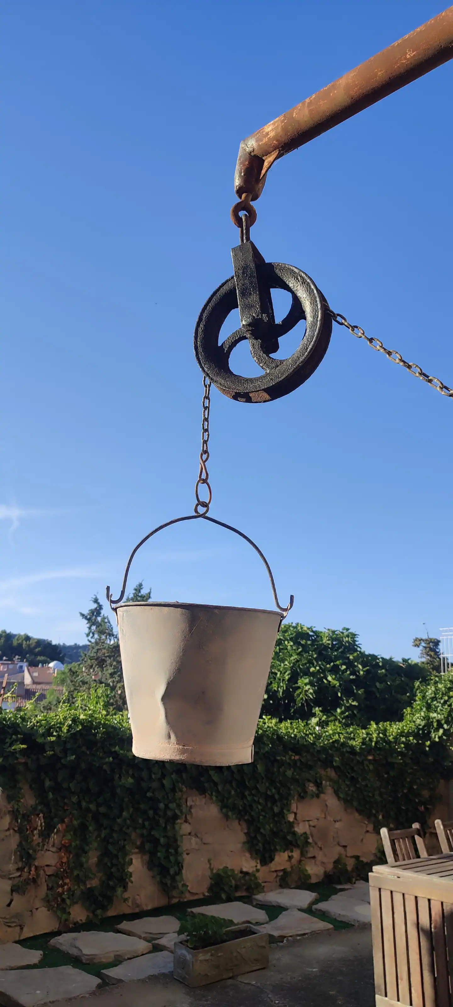 El cubo del pozo colgando de la polea, con el cielo azul detrás