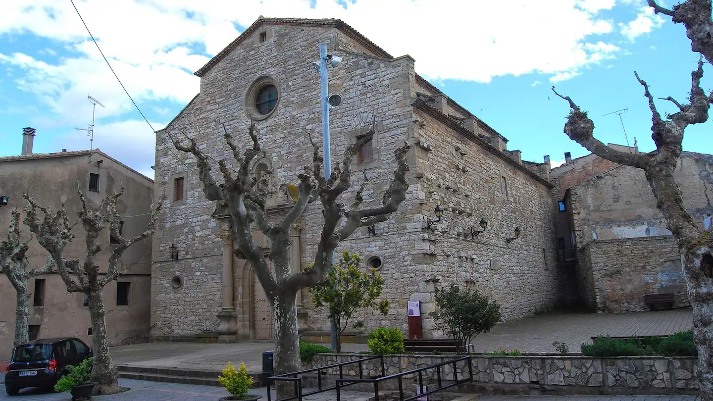 La iglesia románica de Sant Martí Sesgueioles con la plaza y los árboles delante