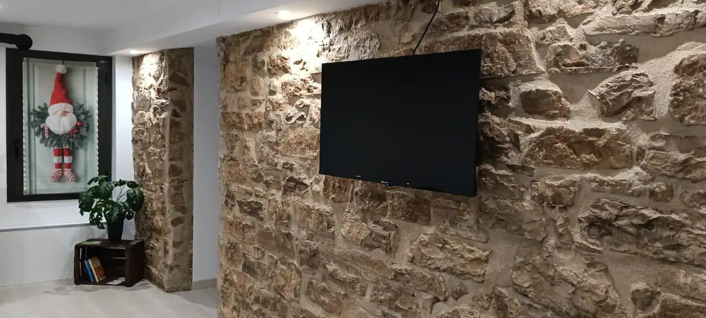 Salón con la pared de piedra vista y la televisión
